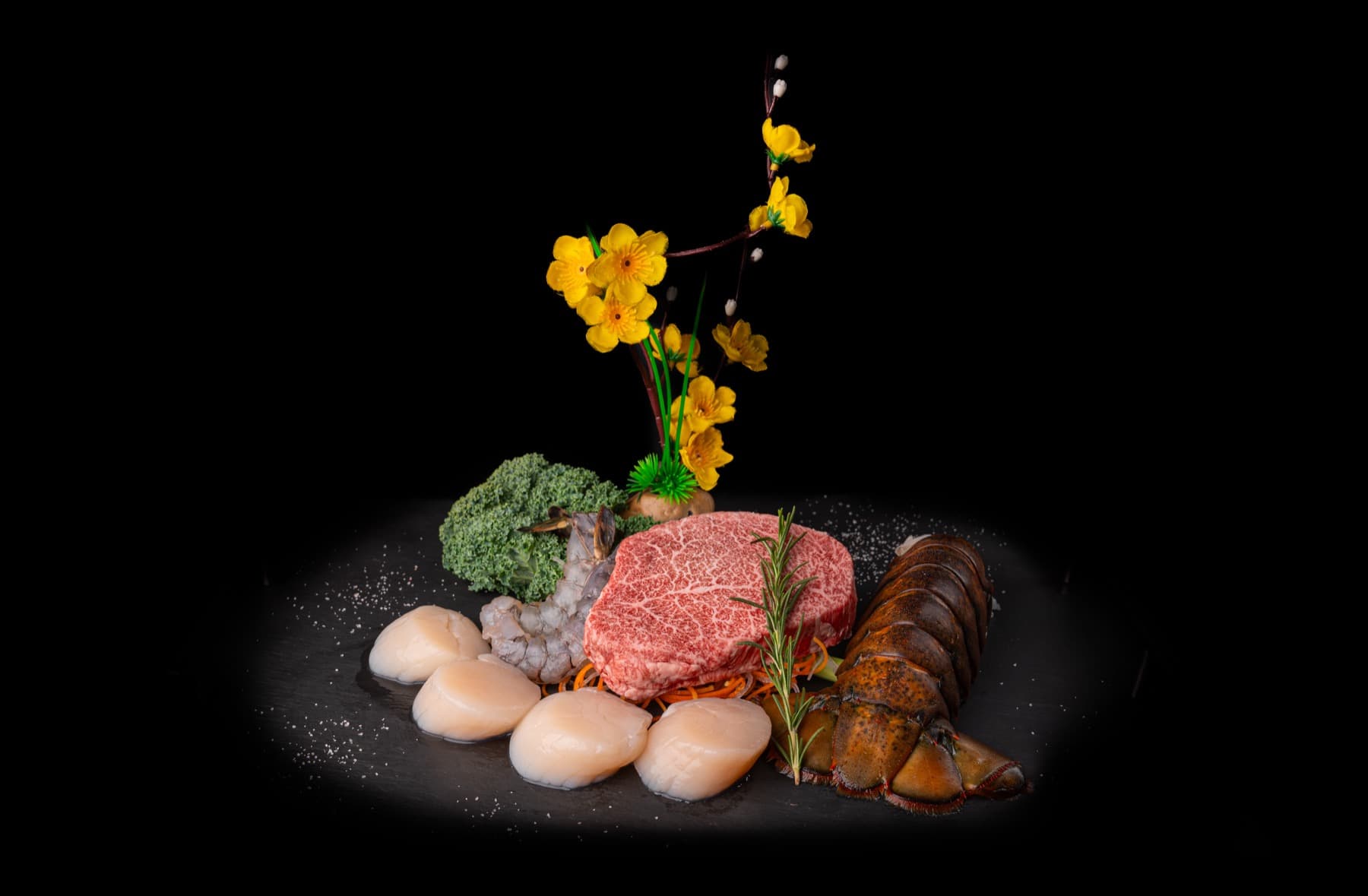 Wagyu filet, scallops and lobster tail arranged with spring blossoms